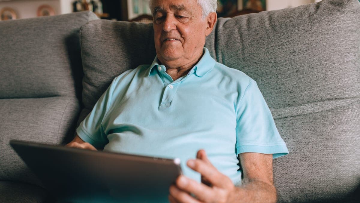 An older man reading in a comfortable chair at home