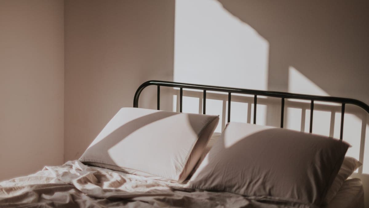 A made bed with white linen in a quiet bedroom