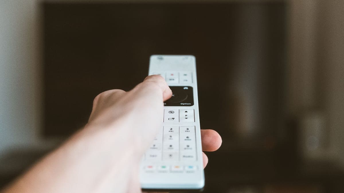 A hand holding a handset, thumb resting on the buttons